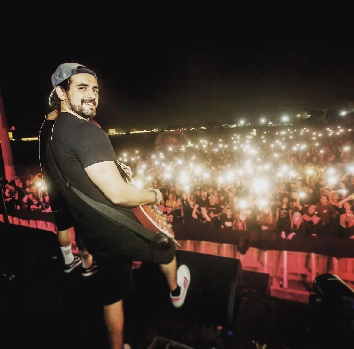 Levi Mynssen no palco diante do público com as luzes dos celulares acesas